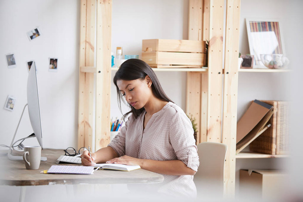 Retrato de una joven mujer de raza mixta que trabaja o estudia sentada en el escritorio en la oficina en casa, espacio para copiar
 - Foto, imagen