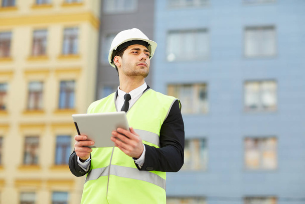 Портрет інженера змішаної раси, який тримає цифровий планшет, що стоїть на будівельному майданчику на відкритому повітрі, копіювати простір
 - Фото, зображення