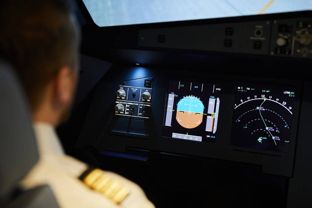 Вид на плече пілота, який сидить на приладовій панелі літака з радіолокаційними лічильниками та планує маршрут польоту
 - Фото, зображення
