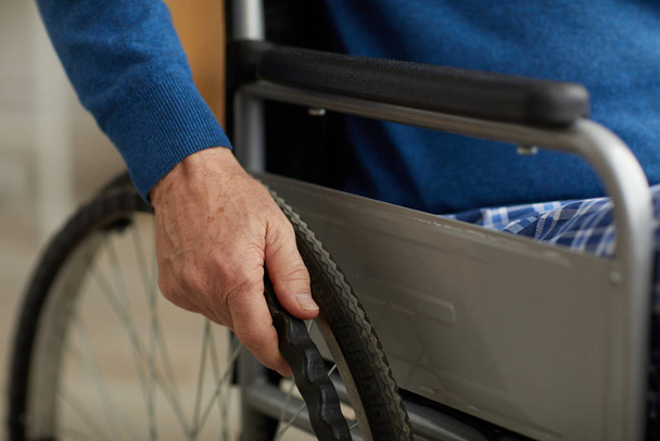Primer plano del hombre mayor discapacitado empujando ruedas de silla de ruedas, espacio para copias
 - Foto, imagen