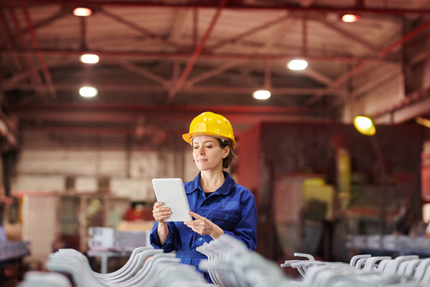 Retrato de cintura hacia arriba de una trabajadora sosteniendo una tableta digital mientras supervisa la producción en la planta, espacio para copiar
 - Foto, imagen