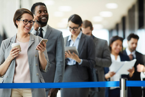 Позитивні амбітні багатоетнічні бізнесмени стоять в черзі за синьою стрічкою і чекають реєстрації на форумі
 - Фото, зображення