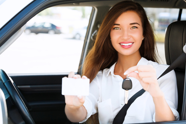 κορίτσι σε ένα αυτοκίνητο που δείχνει ένα κλειδί και μια κενή λευκή κάρτα - Φωτογραφία, εικόνα