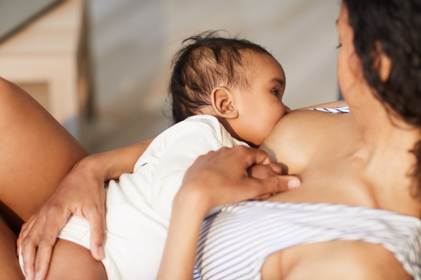 Κοντινό-up της νεαρής μαύρη μητέρα συνδέοντας το μωρό στο στήθος, ενώ δίνοντας θηλή στο γιο κατά τη διάρκεια του θηλασμού - Φωτογραφία, εικόνα