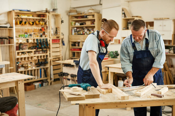 Retrato de dos carpinteros trabajando con madera de pie en la mesa en el taller, espacio de copia
 - Foto, Imagen