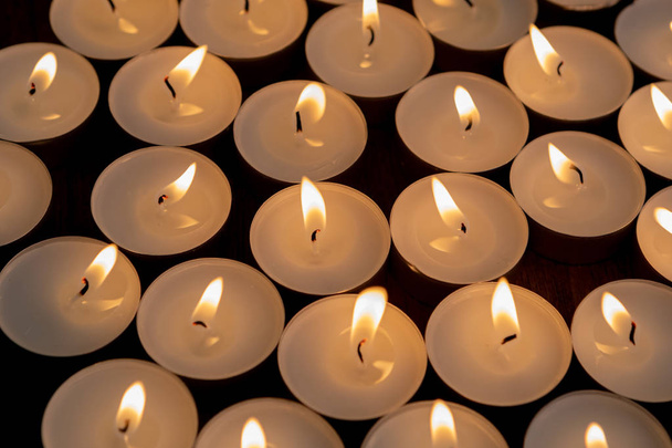 viele kleine brennende Kerzen auf einer Holzoberfläche - Foto, Bild