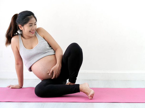 Asian pregnant woman doing yoga at home, lifestyle concept. - Фото, изображение