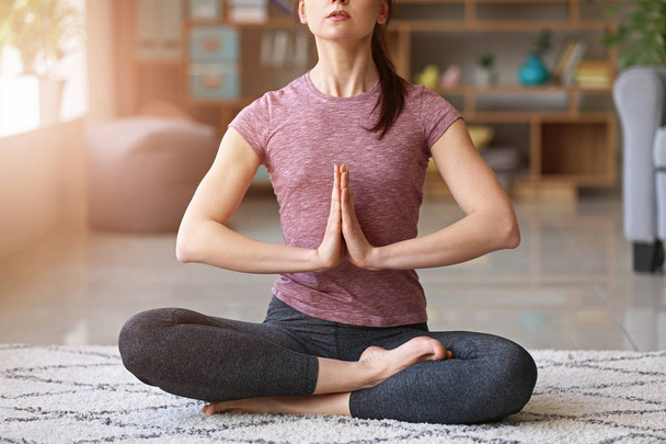 Jonge vrouw die thuis yoga oefent - Foto, afbeelding