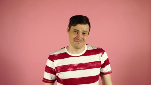 A man in a striped t-shirt on a pink background. Looking camera says yes - Video