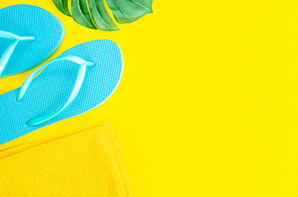 Summer flat lay mockup. Blue flip flops, palm leaf and cloth on yellow background. Top view frame with copy space for travel agency text banner - Photo, Image
