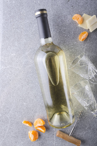 Tiro vertical e vista superior.Vinho branco e pequenos lanches, copos de vinho e saca-rolhas na mesa cinza
 - Foto, Imagem