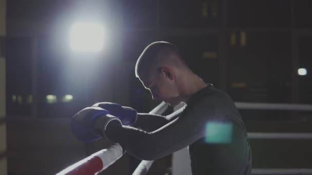 Fighter resting on ropes of ring. Kickboxer training in smoky studio - Filmati, video