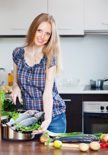 Smiling woman cooking lubina in skillet - Фото, зображення