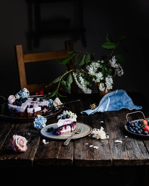 Slice of blueberry cheesecake decorated with flowers on ceramic plate  - Fotografie, Obrázek