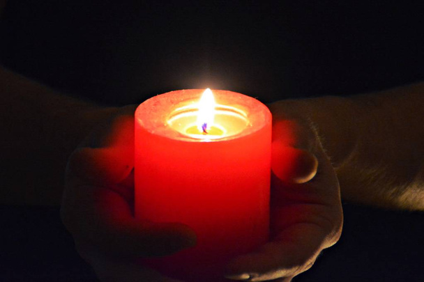 trzymając czerwoną świeczkę w ciemności z bliska  - Zdjęcie, obraz