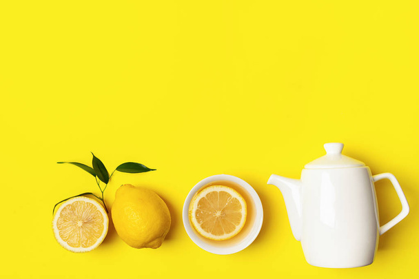 Chá de limão fresco ou bebida de desintoxicação em uma xícara branca e um bule de chá em um fundo amarelo brilhante. Conceito de alimentação saudável
. - Foto, Imagem