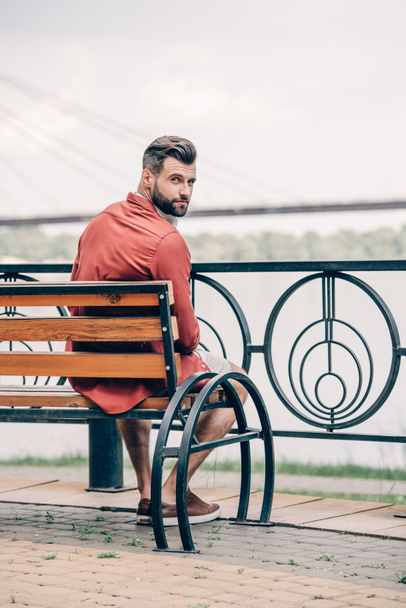 handsome man sitting on bench and looking at camera - Фото, зображення