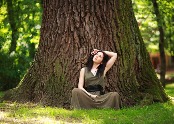Girl in dress sits enjoying nature meditates, practices yoga - Photo, image