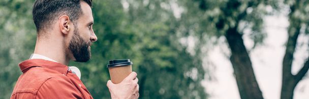 panoramic shot of man holding coffee to go and looking away - Photo, Image