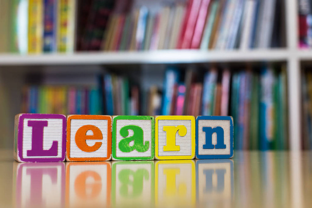 Алфавит блокирует написание слова "учиться" перед книжной полкой
 - Фото, изображение