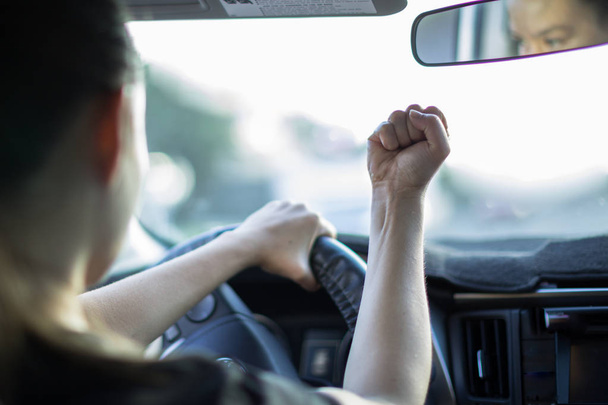 Nieustraszona młoda kobieta kierowca wściekły wściekłość drogowego, za kierownicą samochodu. - Zdjęcie, obraz
