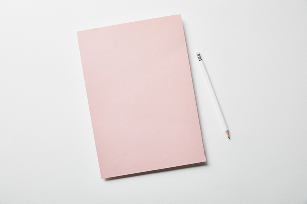 top view of pink paper and pencil on white surface - Photo, Image