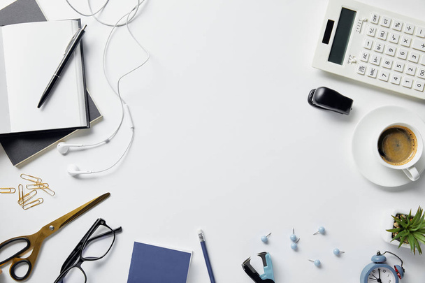 top view of plant, glasses, coffee, earphones and office supplies on white surface - Foto, Imagem