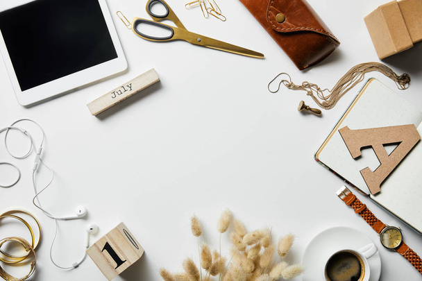 top view of smartphone, notepad, case, earphones, plants, office supplies and coffee with jewelry on white surface - Foto, immagini