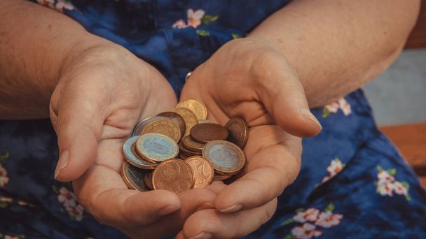 Vanha nainen kerjää almuja. Rahan ja metallirahojen lähikuva
 - Valokuva, kuva