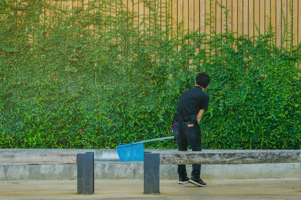 Młody człowiek czyszczenia fontanny basen z upadłych liści z netto  - Zdjęcie, obraz