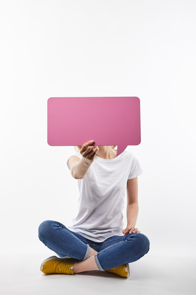 mulher com bolha de fala rosa na mão sentado isolado no branco
 - Foto, Imagem