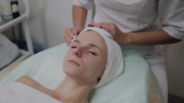 Egy gyönyörű nő kozmetikus arcát egy pamut pad előtt az eljárás. - Felvétel, videó