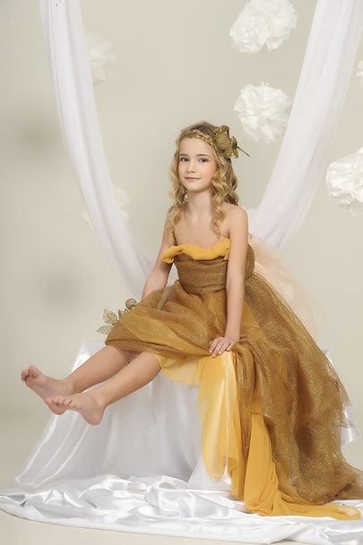 Portrait of a beautiful girl in a gold dress - Foto, imagen