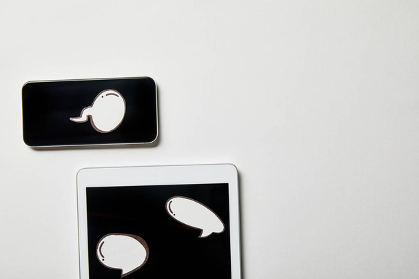 Digitální tablet a smartphone s papírovým promyšleným papírem a s bublinami na bílém povrchu - Fotografie, Obrázek
