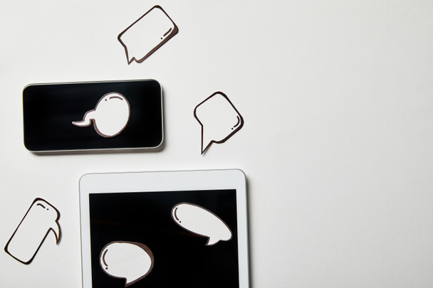 beyaz yüzeyüzerinde kağıt düşünce ve konuşma kabarcıkları ile dijital tablet ve akıllı telefon - Fotoğraf, Görsel