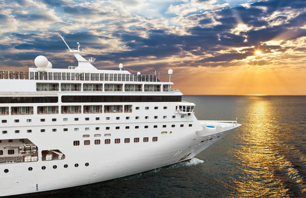 Luxury cruise ship sailing from port on sunset  - Фото, изображение