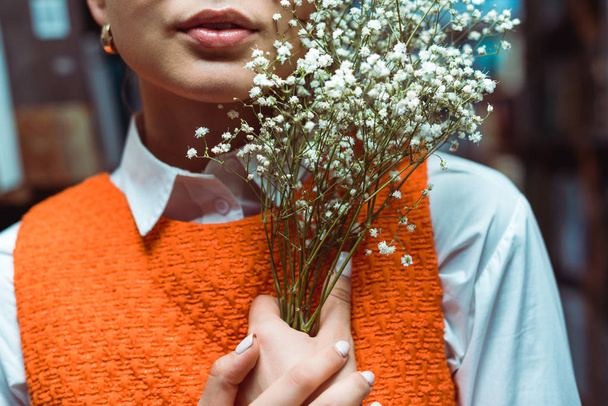 обрізаний вид молодої дорослої жінки, що тримає білі квіти
  - Фото, зображення