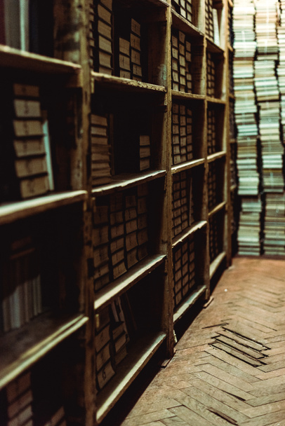 επιλεκτική εστίαση των ρετρό βιβλία σε ξύλινα ράφια στη βιβλιοθήκη  - Φωτογραφία, εικόνα