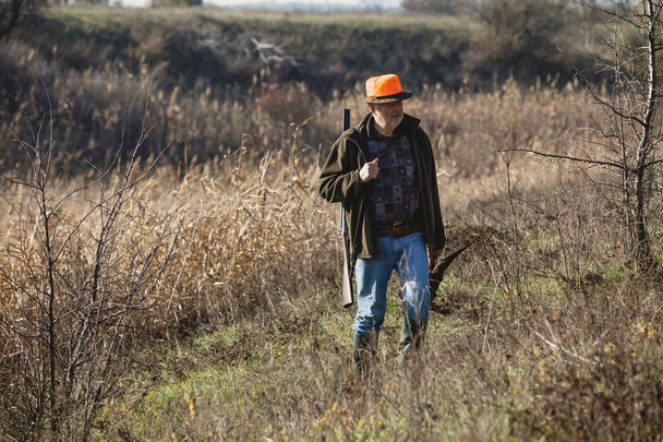 Elderly hunter with wild bird in orange hat - Fotografie, Obrázek