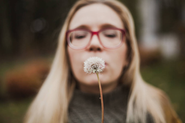 Slender blonde with long hair blowing on dandelion - Photo, Image