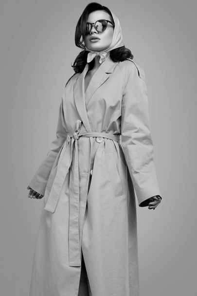 Fiatal elegáns barna nő kabátban és kendőben pózol a stúdióban - Fotó, kép