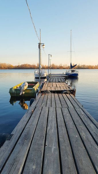 Пирс с лодками в осенней гавани на закате
 - Фото, изображение