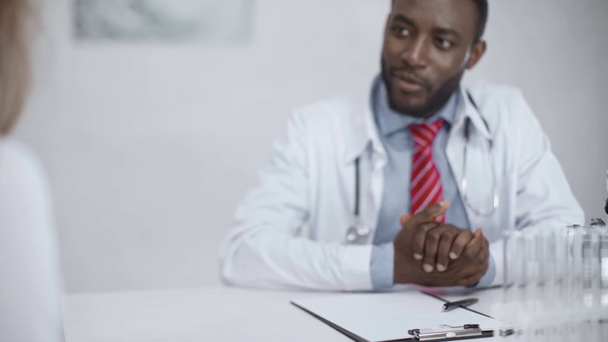 medico afroamericano che stringe la mano al collega e sorride mentre si siede sul posto di lavoro in ospedale
 - Filmati, video