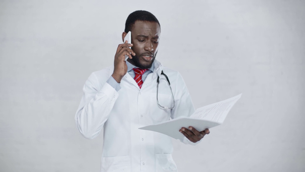 bonito Africano americano médico falando no smartphone e segurando pasta - Filmagem, Vídeo