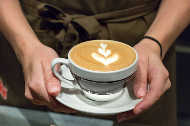 Femme barista servir avec ses mains un cappuccino juste fait
. - Photo, image