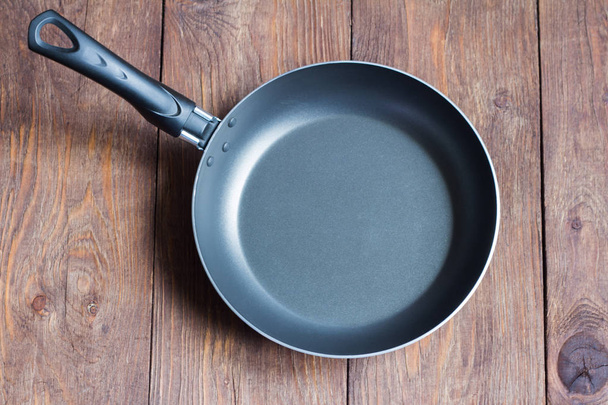 empty frying pan with non-stick coating on wooden background - Foto, Imagem