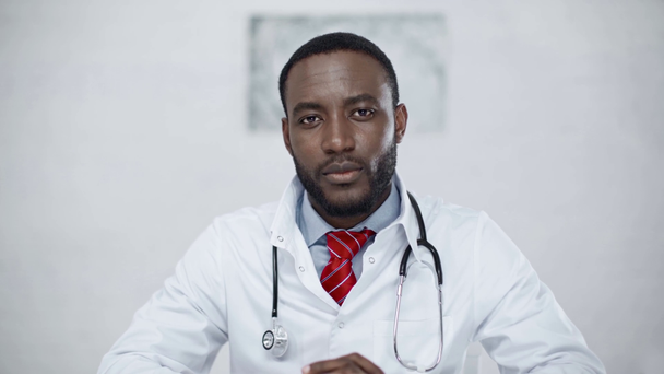 guapo, positivo afroamericano médico sonriendo mientras mira a la cámara
 - Imágenes, Vídeo
