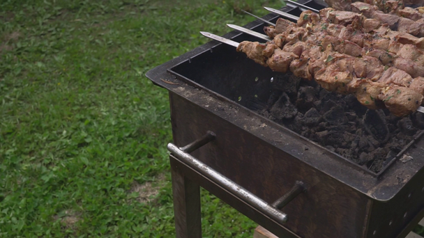 Volný čas, jídlo, lidé a prázdniny koncept. vaří maso na ohni na pouliční párty. vaření masa na grilu - Záběry, video