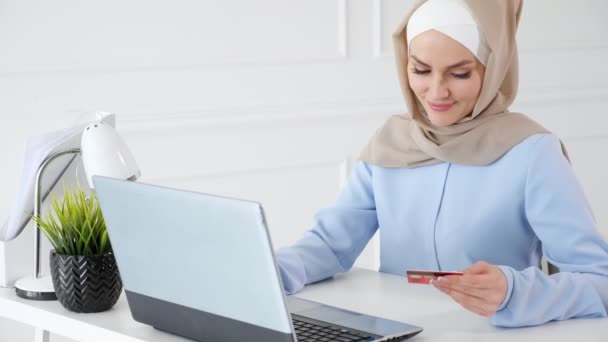 Muslim woman in hijab is buying online with a credit card and laptop. - Footage, Video