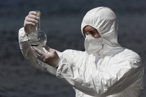ispettore dell'acqua in costume protettivo, respiratore e occhiali con fiaschetta con campione d'acqua
 - Foto, immagini